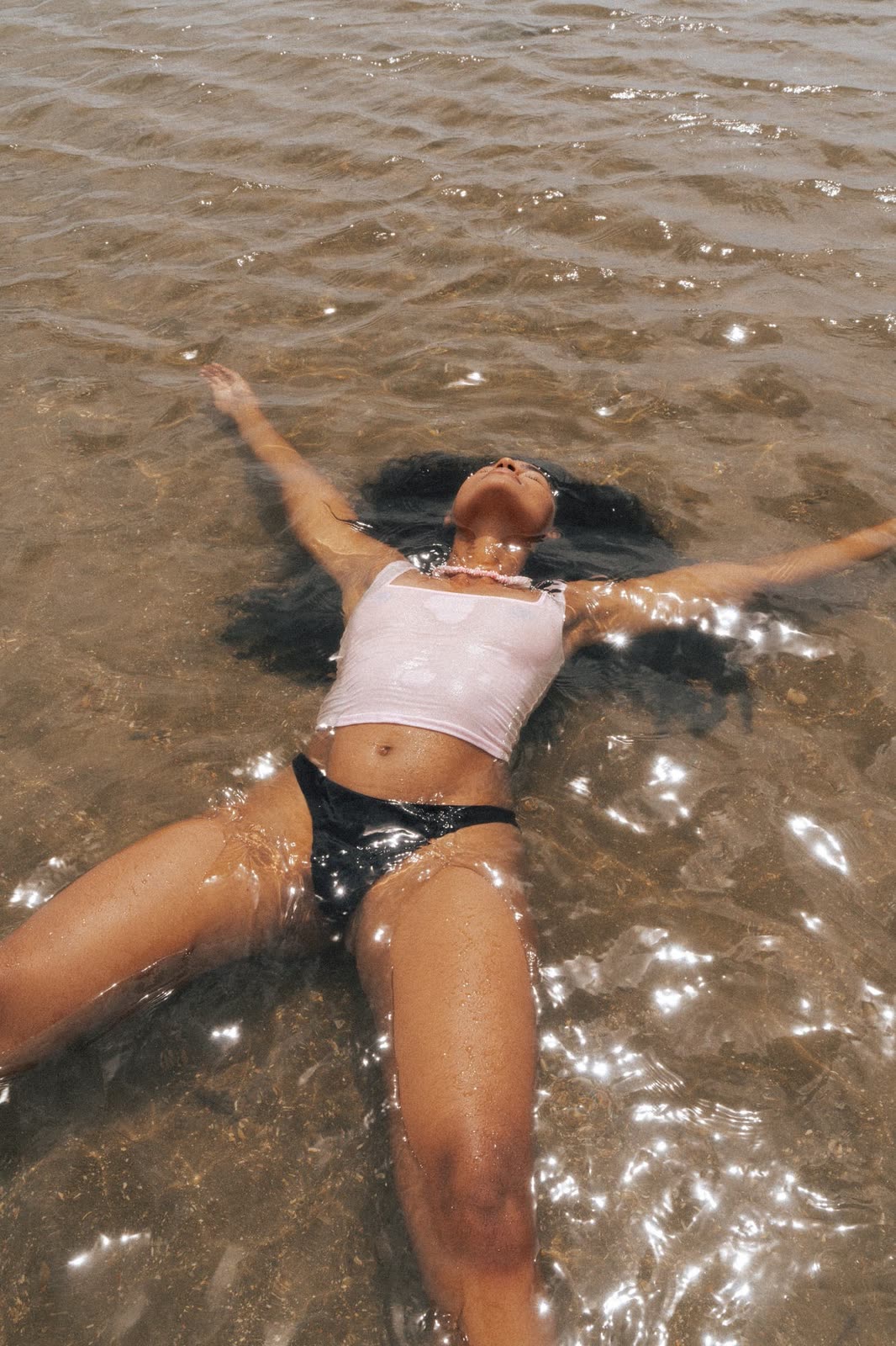Model floating on her back in shallow sunlit water — LAILA, by Kenneth Kemp
