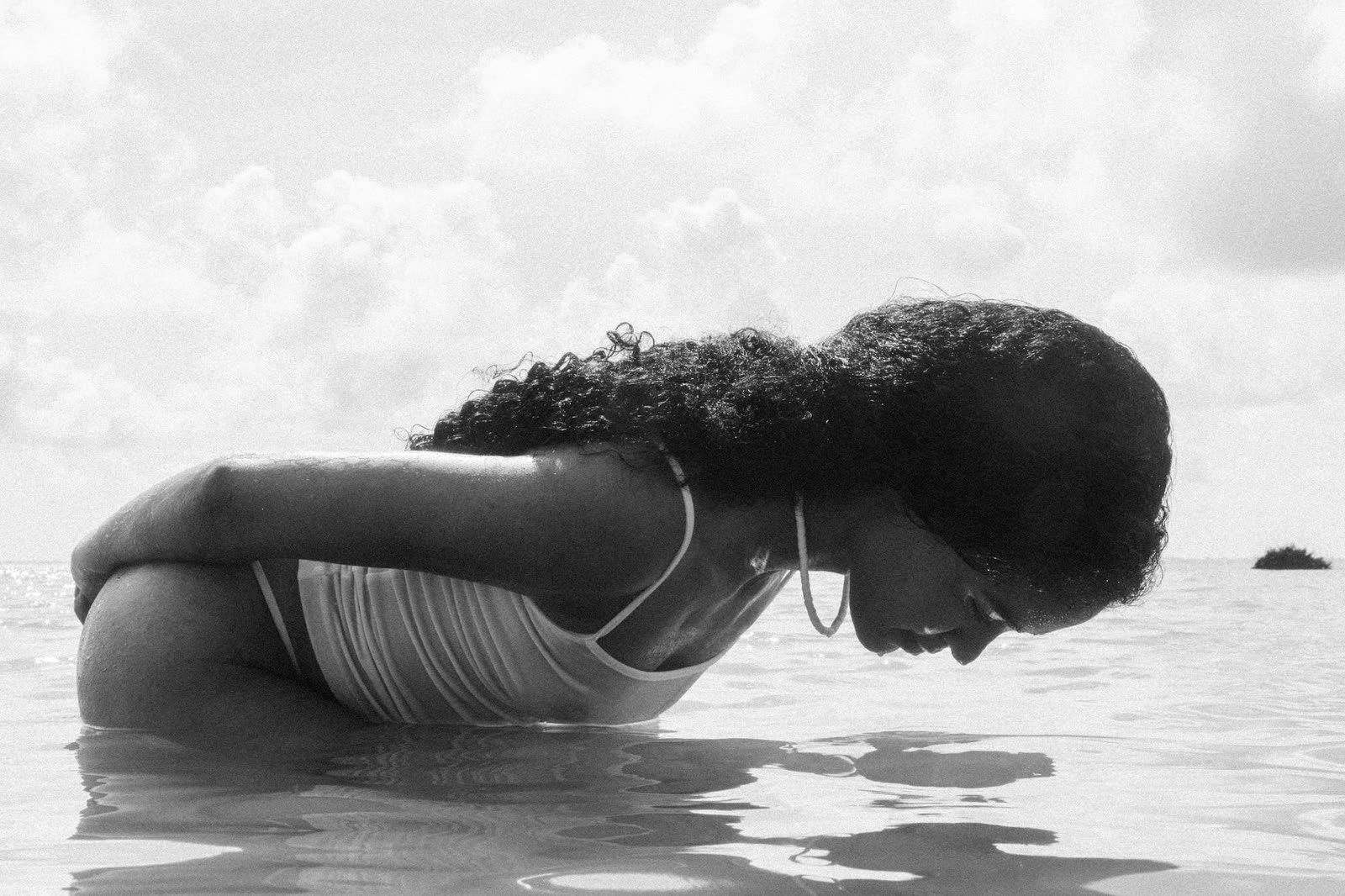Black and white frame of a model leaning into shallow water — LAILA, by Kenneth Kemp
