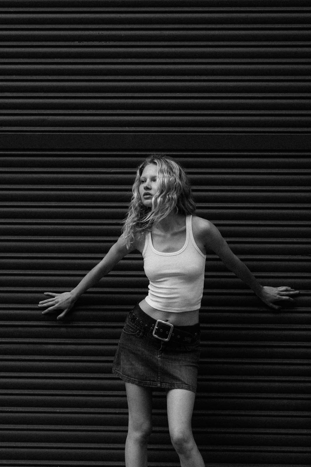 Black and white frame of a blonde model against a corrugated shutter — NIKA, by Kenneth Kemp